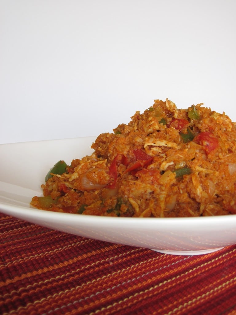 A white bowl of spanish rice on a red woven placemat.