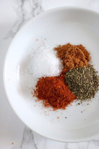 Four spices in a mound together on a white plate.