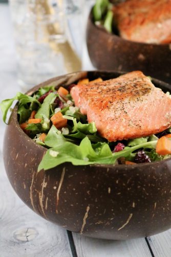 Up close of a salmon salad. Sweet potato, quinoa, and cranberries are visible.