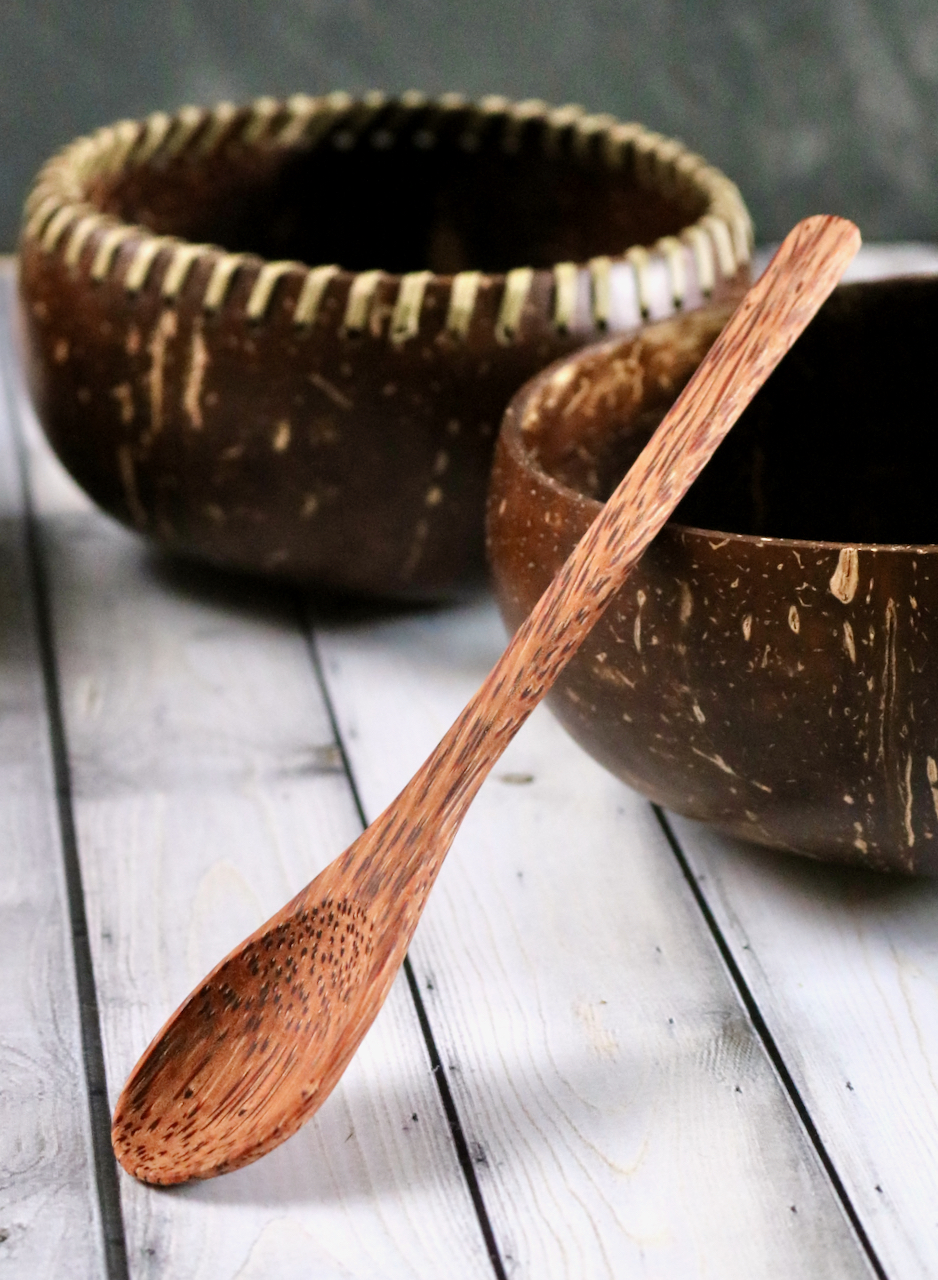 A spoon made from coconut timber propped up against a coconut shell repurposed as a bowl.