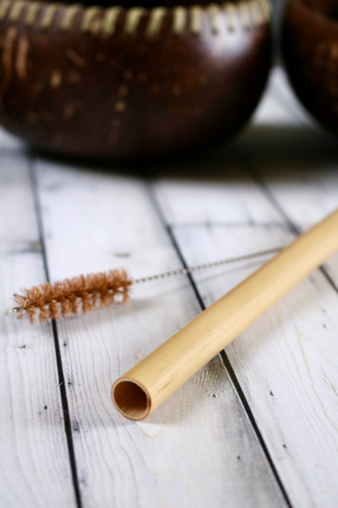 Up close of one end of a bamboo boba straw with a straw cleaning brush off to its side.