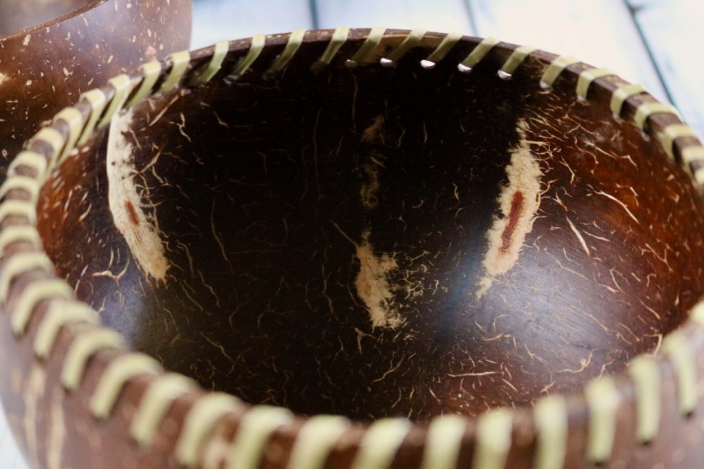 Inside detail of a coconut shell bowl with fiber lacing around the top.