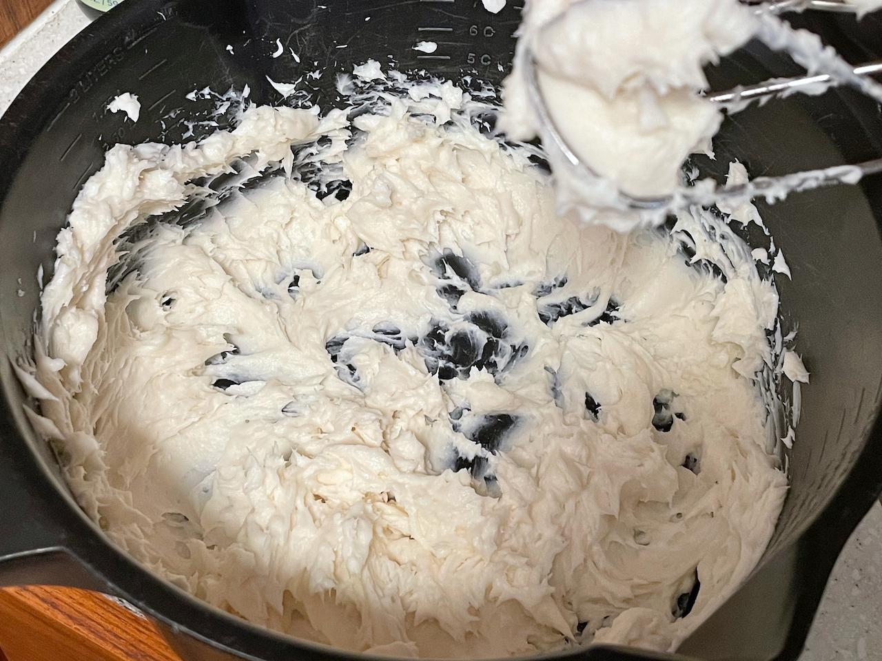 A black mixing bowl filled with whipped dairy free cream cheese alternative.