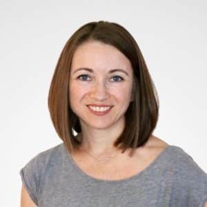 Headshot of Meagan in a gray top against a very light gray background.